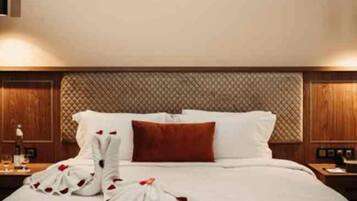 A hotel room with a neatly made bed, a wooden headboard, and a nightstand with a lamp.