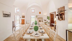 A spacious dining area with a long table set for a meal, surrounded by white chairs. - Masseria Samali 14+4, Emma Villas (Leverano)