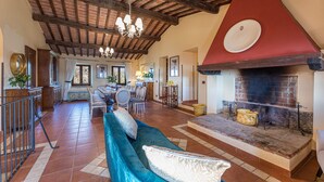 A spacious living area with a fireplace, a dining area with a long table and chairs, and a seating area with a blue sofa.
