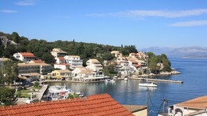 A coastal town with buildings along the waterfront, a marina with boats, and a clear view of the sea.