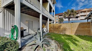 A multi-story building with a covered porch, a wooden fence, and a well-maintained lawn. - Lucky Ducky | Easy Walk to Beach + Pet Friendly! (Carolina Beach)