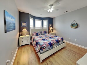 Een slaapkamer met een bed, twee nachtkastjes, een plafondventilator en een wandlamp.
