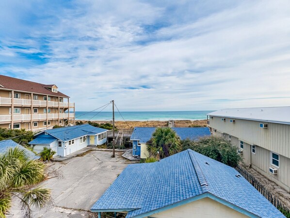 A coastal hotel with multiple buildings, a beach view, and a clear sky.
