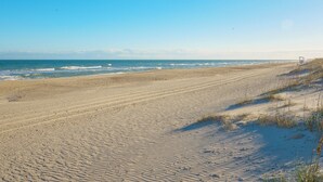 Una playa extensa de arena con olas suaves y cielo despejado.
