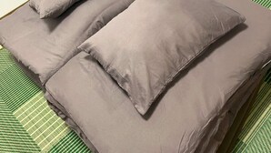 Una cama con varias almohadas y un edredón verde a rayas.