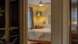 A bedroom with a bed, a ceiling fan, and a bedside lamp. - Charming Cottage with Hot Tub, Fire Pit, & Wooded Backyard (Saint Paul)