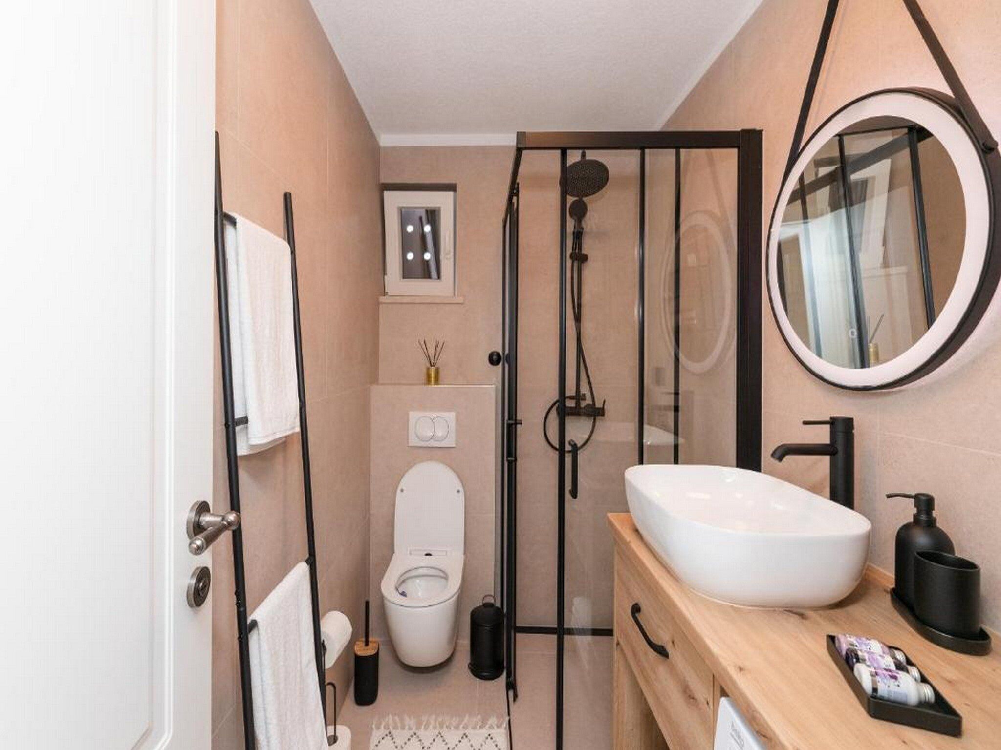 A modern bathroom with a glass-enclosed shower, a white toilet, and a wooden vanity with a white sink.