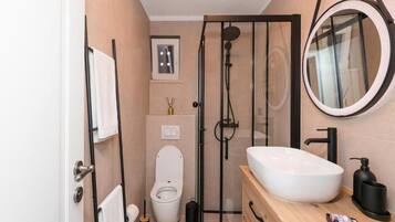 A modern bathroom with a glass-enclosed shower, a white toilet, and a wooden vanity with a white sink.