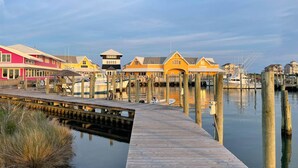 A waterfront property with multiple buildings, a wooden dock, and boats. - Oceanfront Condo w/ Private Deck, Resort Pool, Hot Tub, Clubhouse, Beach Access (Hatteras)