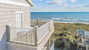 A beachfront property with a balcony overlooking the ocean, a deck with chairs, and a view of the beach and sea. - Oceanfront Condo w/ Private Deck, Resort Pool, Hot Tub, Clubhouse, Beach Access (Hatteras)