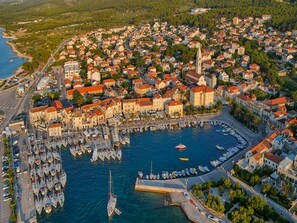 An aerial view of a coastal town with a marina filled with boats, surrounded by densely packed buildings with red roofs. - Apartment Marijana (Supetar)