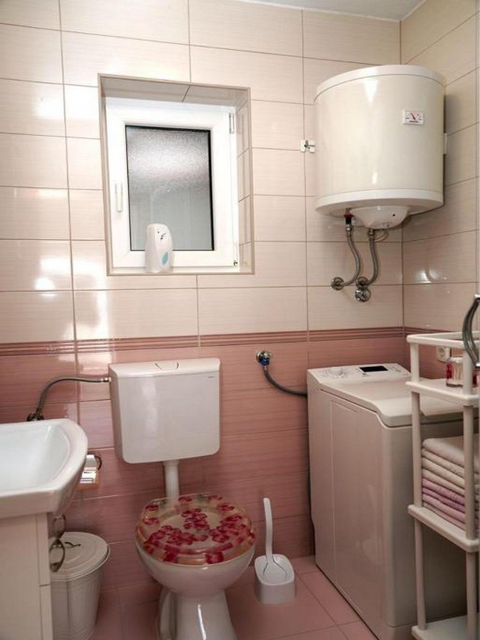 A bathroom with a toilet, sink, and a small window.