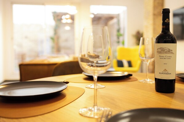 Uma mesa de jantar com copos de vinho e uma garrafa de vinho Dona Clara Douro DOC 2017.
