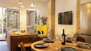 A dining area with a wooden table set for four, a yellow armchair, and a sofa with cushions. - Stylish Boutique Design Apartment Central Location with Terrace (València)