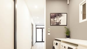 A laundry room with two washing machines, a potted plant, and a framed picture on the wall. - Stylish Boutique Design Apartment Central Location with Terrace (València)
