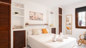 Una habitación de hotel con una cama grande, un armario de madera, paredes blancas y un cuadro.
