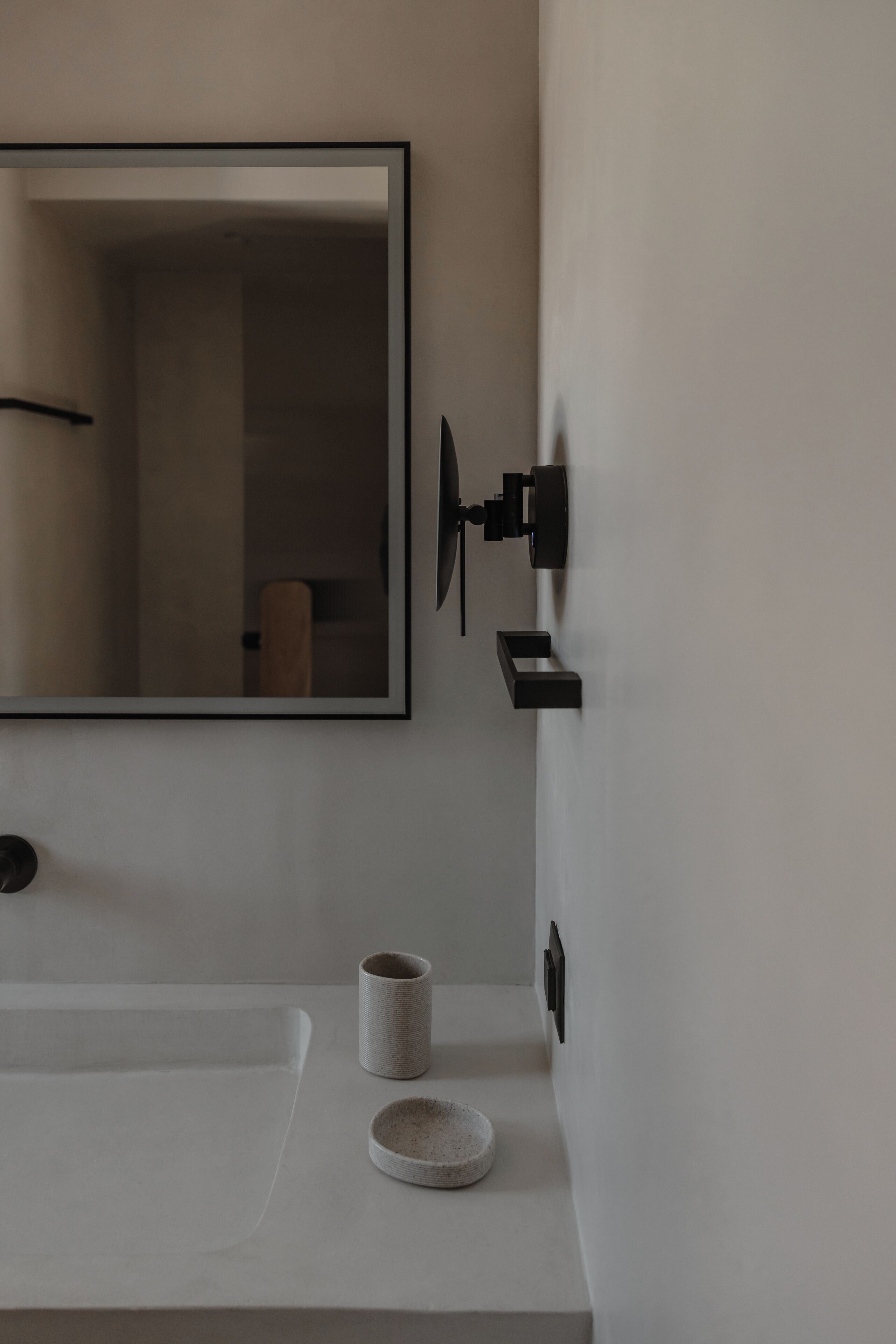 A bathroom with a white sink, a mirror, a towel, and a black towel rack.