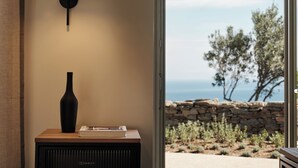 A room with a wall-mounted lamp, a black vase, and a book on a wooden table. - Stamna Sifnos, a member of Design Hotels (Sifnos)