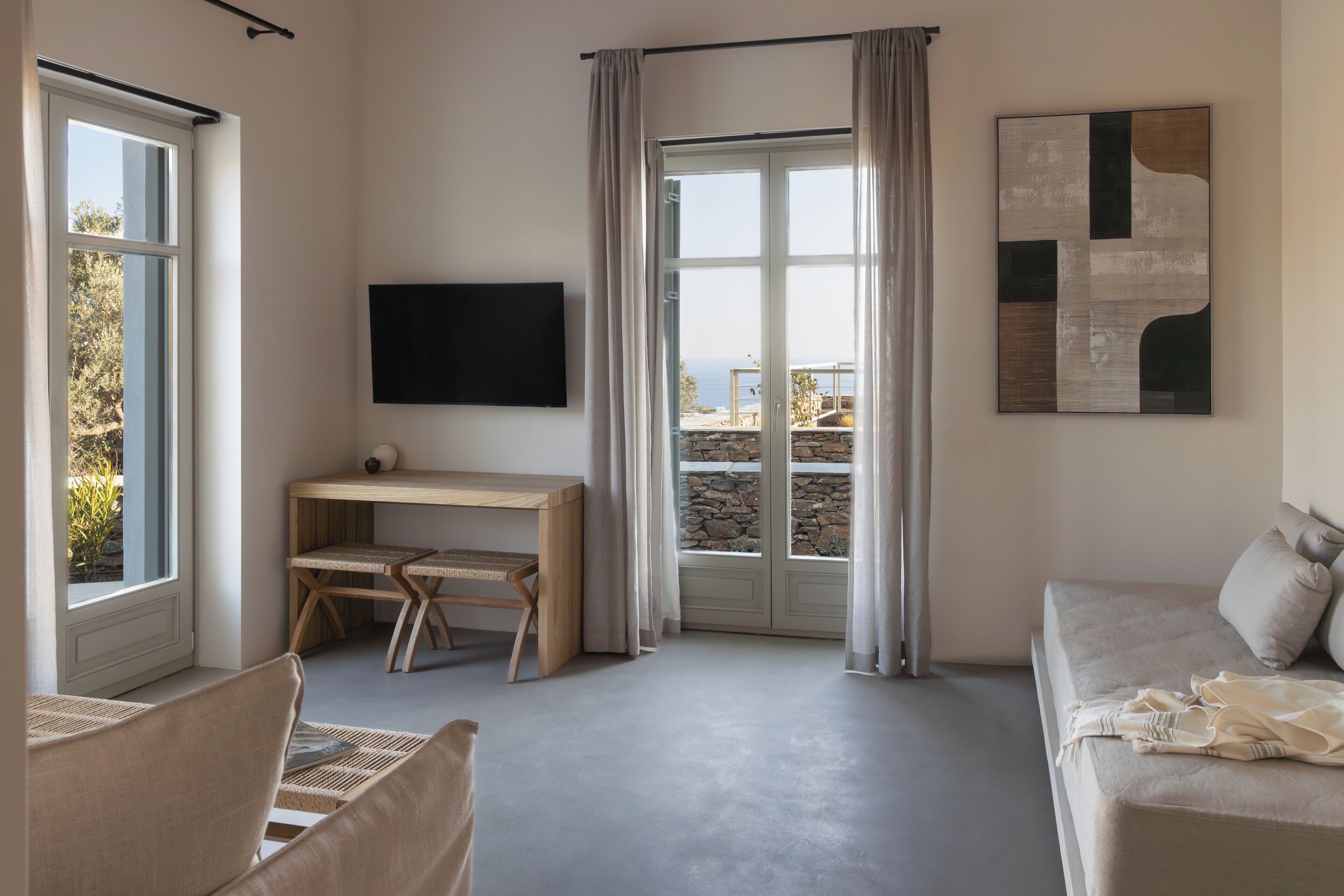 Una habitación moderna con un ventanal grande, un escritorio, un sofá y un televisor.