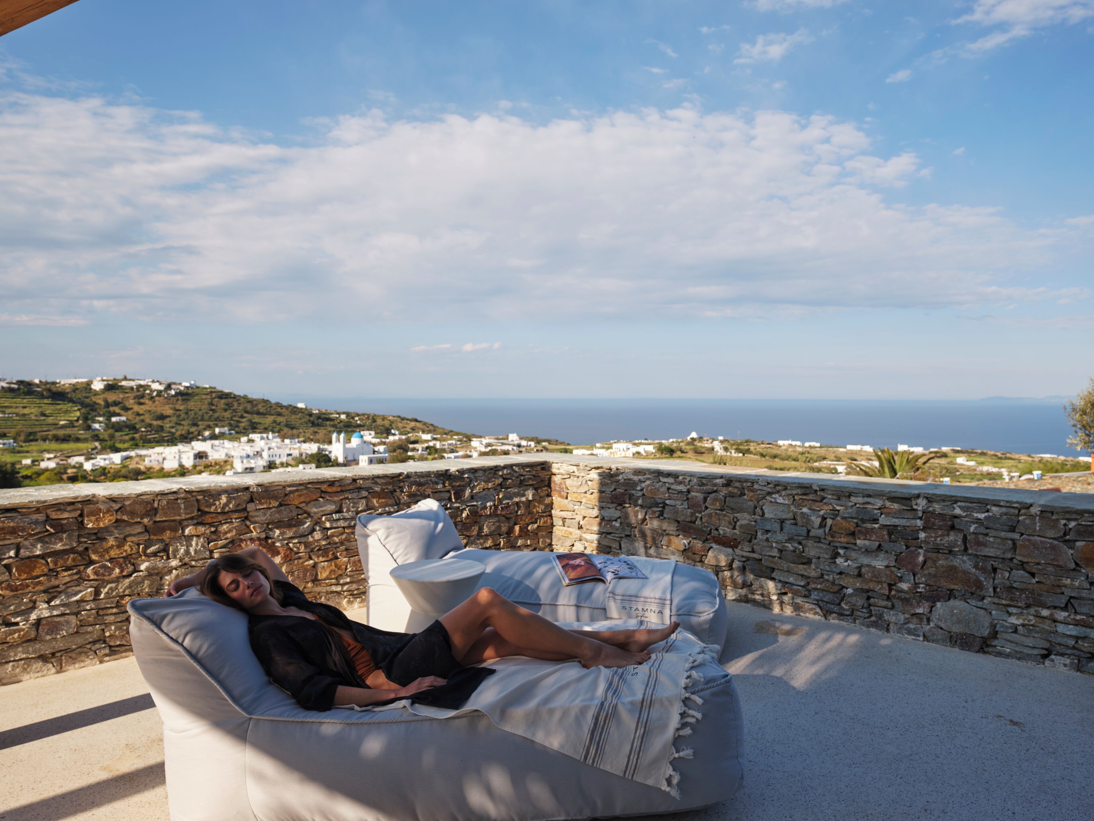 Una persona descansando en una silla blanca acolchada, con vistas a un paisaje costero.