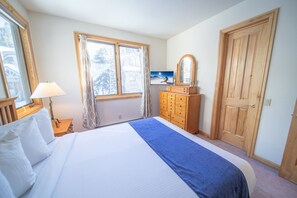A bedroom with a bed, a dresser, a mirror, and a window with curtains. - Walk to ski slopes! Private hot tub and garage! (Keystone)