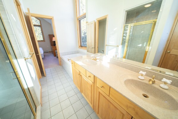 A modern bathroom with two sinks, wooden cabinets, and a large mirror. - Walk to ski slopes! Private hot tub and garage! (Keystone)