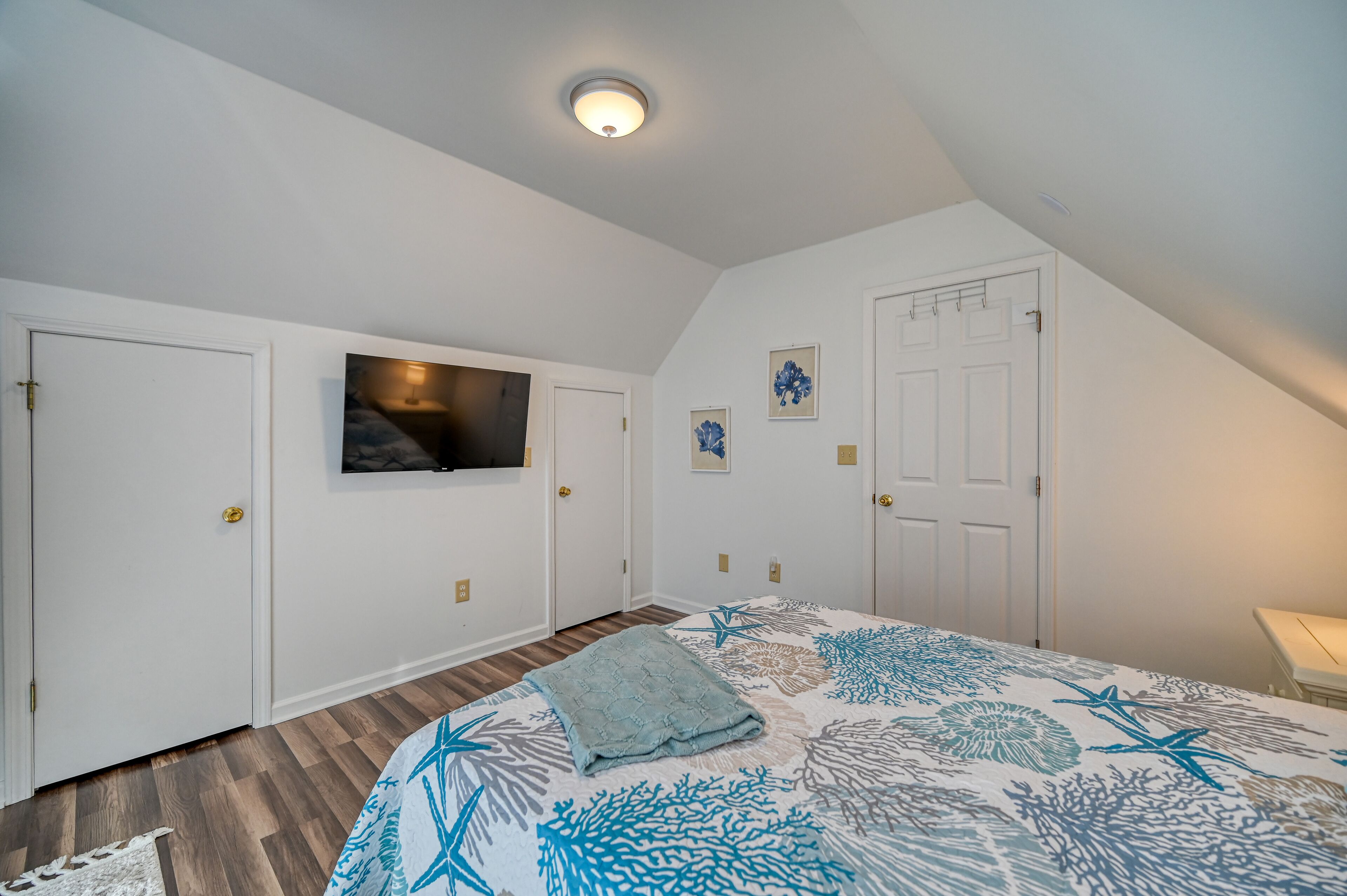 A bedroom with a bed, a television mounted on the wall, and a door with a handle.