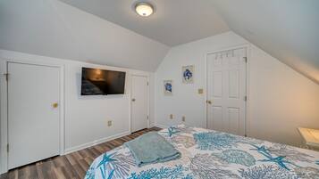 A bedroom with a bed, a television mounted on the wall, and a door with a handle.