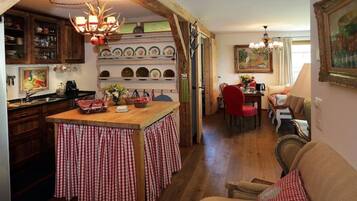 Une cuisine chaleureuse avec un îlot central, des meubles en bois et un coin repas comprenant une chaise rouge et un canapé.