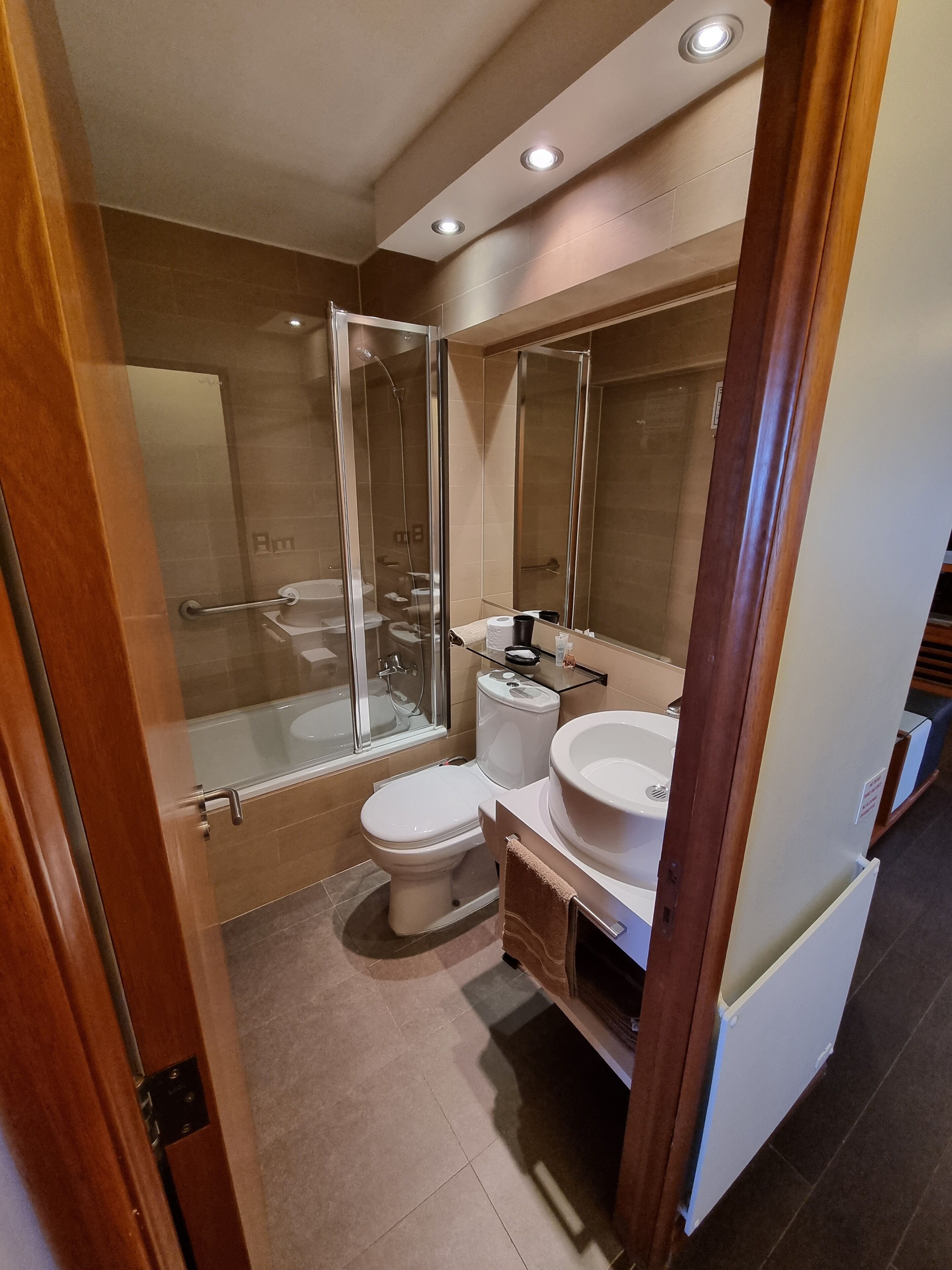 A modern bathroom with a glass-enclosed shower, a toilet, and a sink.