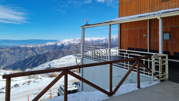A wooden building with a balcony overlooking a snowy mountain range. - Habitamar El Colorado (Lo Barnechea)