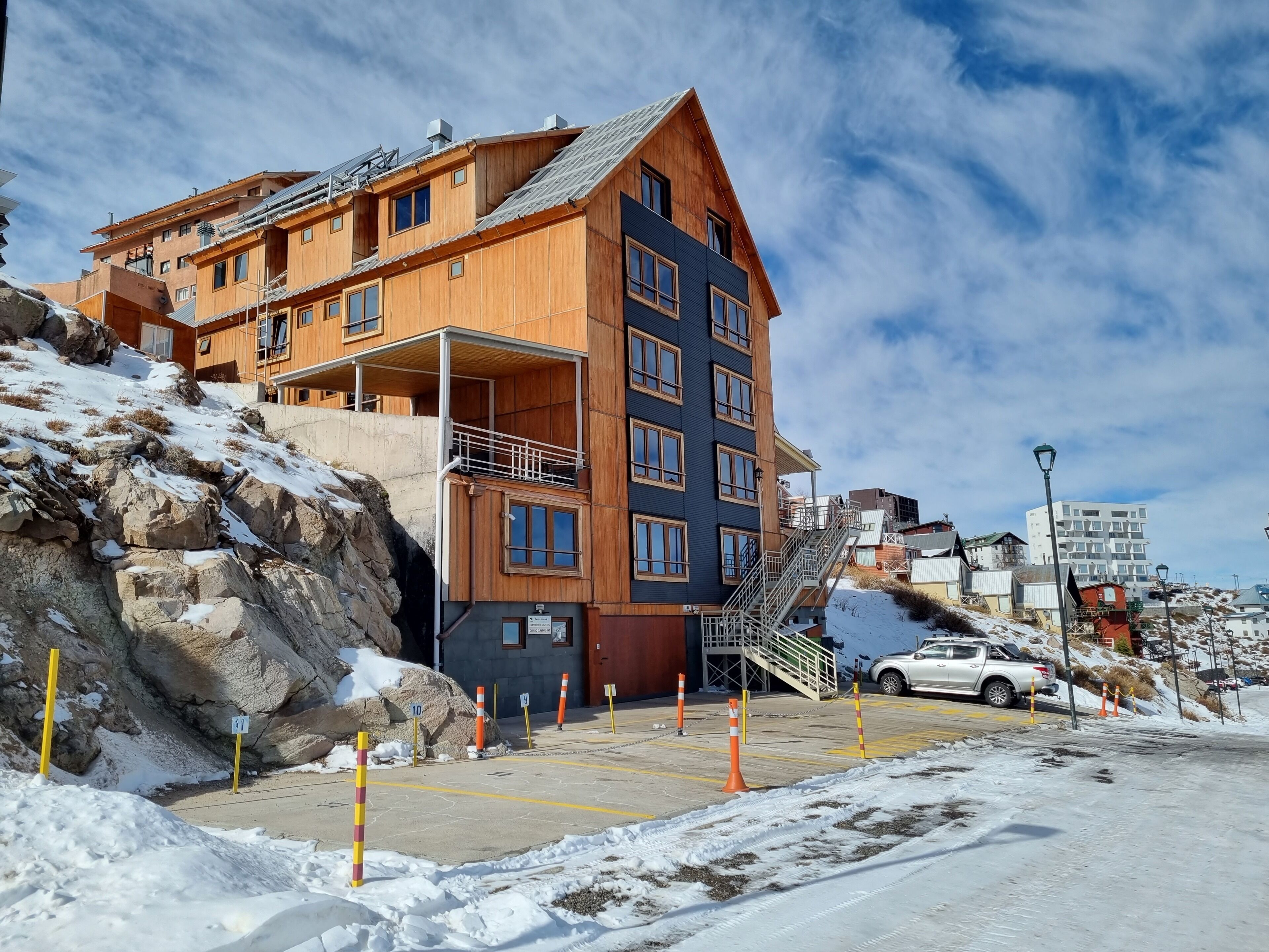 A multi-story building with a wooden facade, a balcony, and a staircase leading to the entrance.