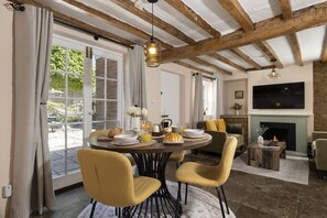 Un espace repas comprenant une table ronde, des chaises et une cheminée.