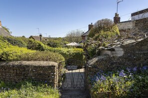 A stone gate with a sign reading 'Orchard Cottage' leading to a stone wall.