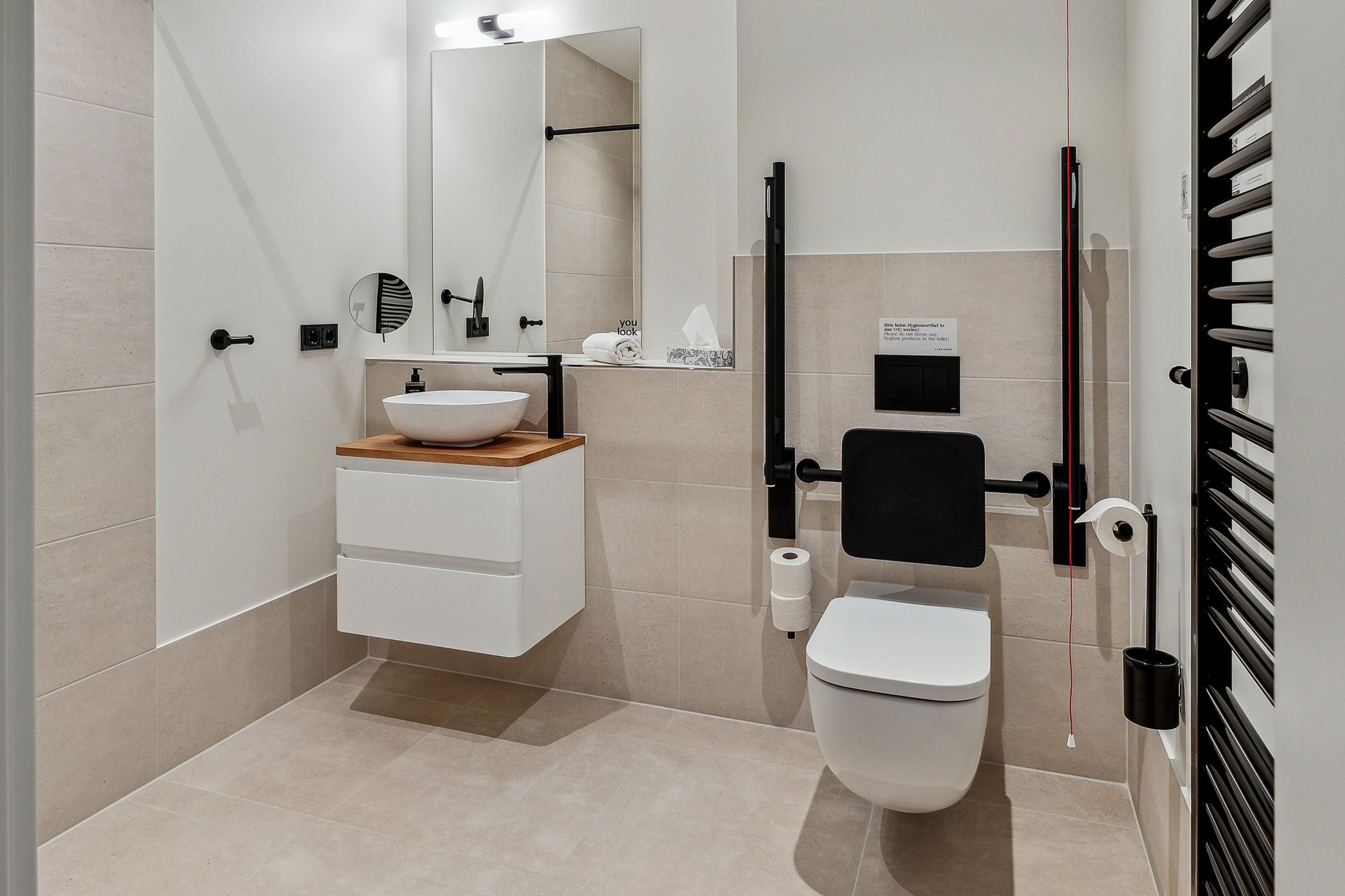 Un baño moderno con lavamanos blanco, espejo, inodoro y cabina de ducha.