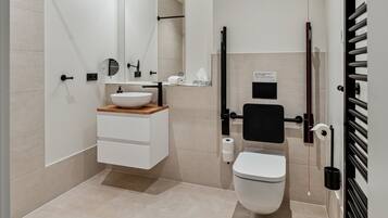Un baño moderno con lavamanos blanco, espejo, inodoro y cabina de ducha.