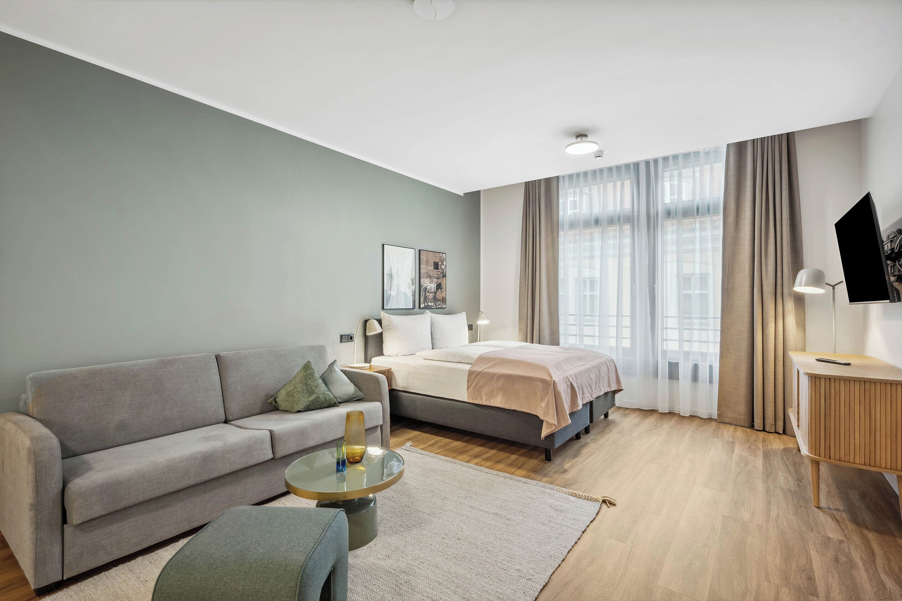 Una habitación de hotel moderna con una cama, sofá y una pequeña mesa.