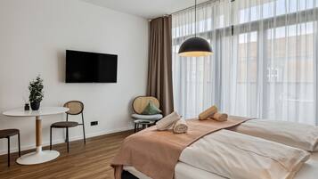 Et moderne hotelværelse med seng, fjernsyn, spisebord og stol.