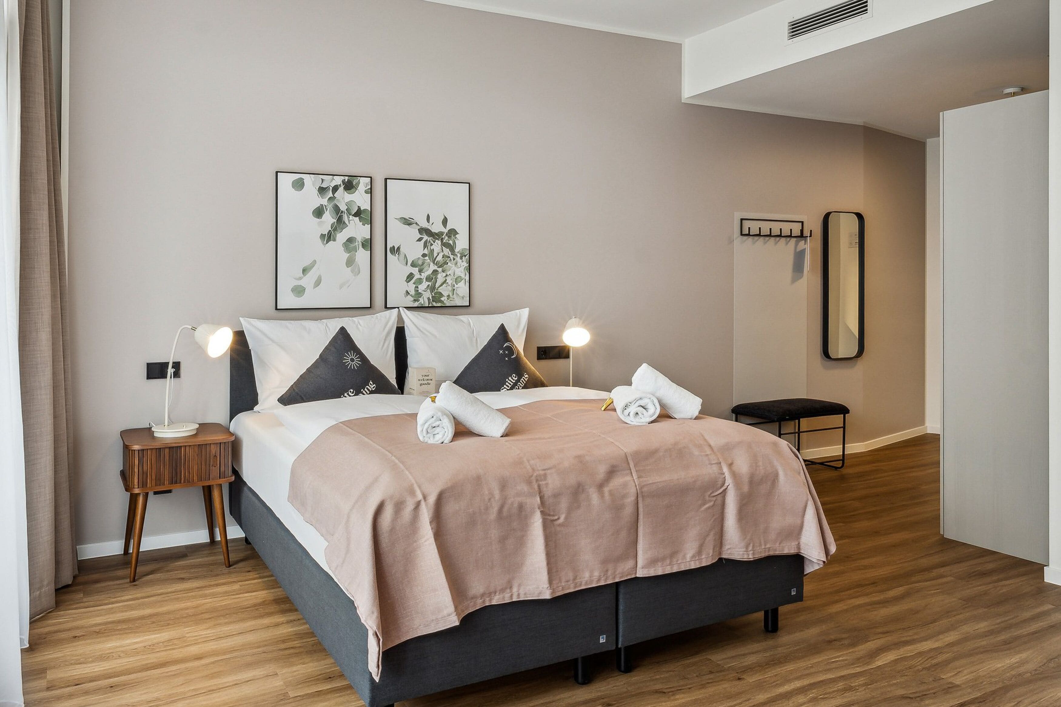 A modern bedroom with a bed, bedside tables, a mirror, and artwork on the wall.