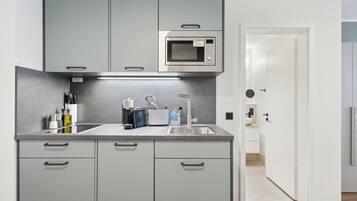 A modern kitchen with grey cabinets, a stainless steel microwave, and a sink.