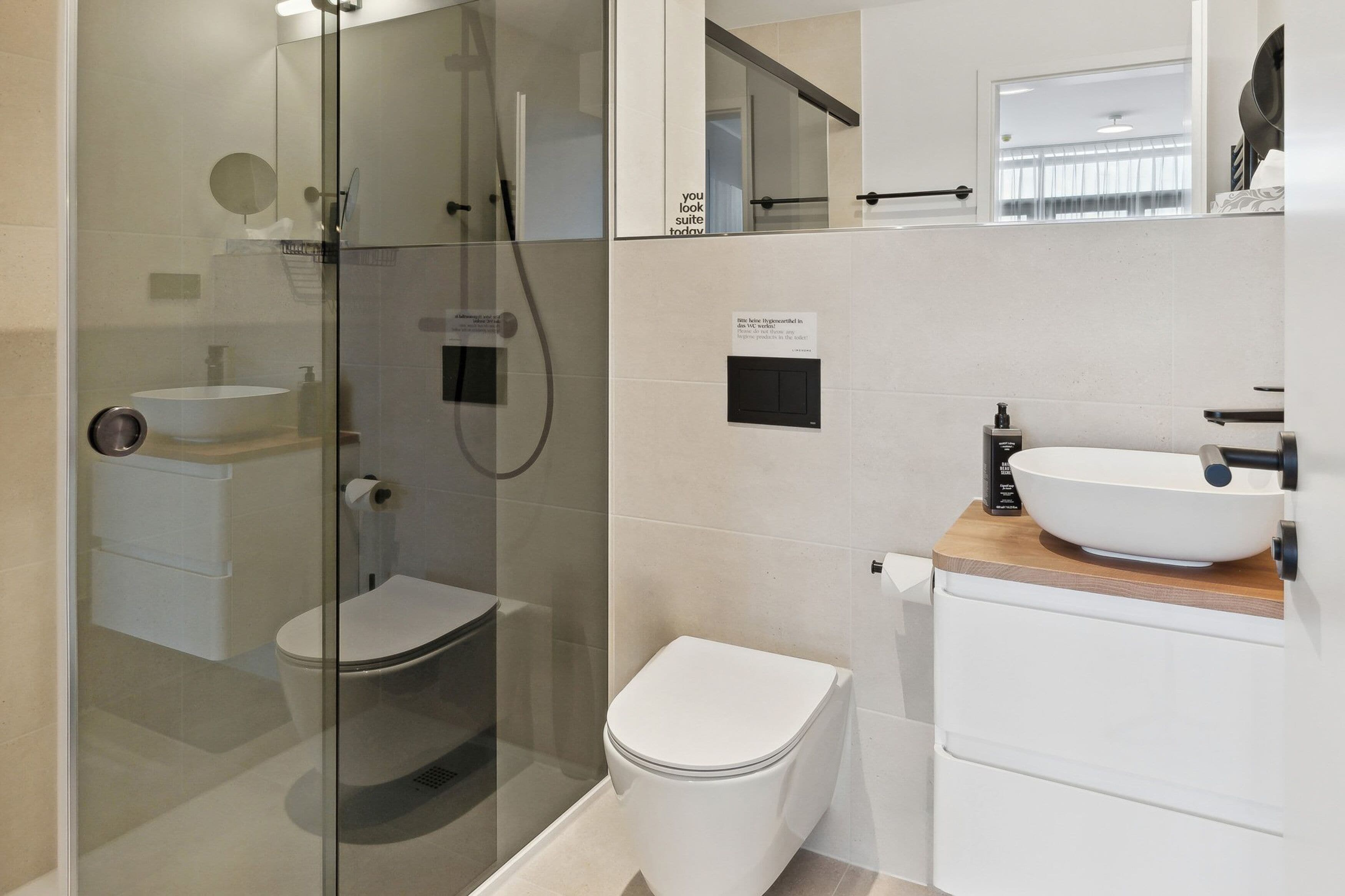 A modern bathroom with a glass-enclosed shower, a white toilet, and a vessel sink.