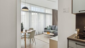 Un saló modern amb un sofà, una taula de centre i una zona de menjador. Hi ha una cuina amb fogons i armaris.