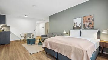 A modern hotel room with a large bed, a desk, and a seating area.