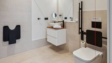 A modern bathroom with a toilet, sink, and mirror.