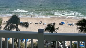 Ein Strand mit Wellen, Palmen und blauem Himmel.