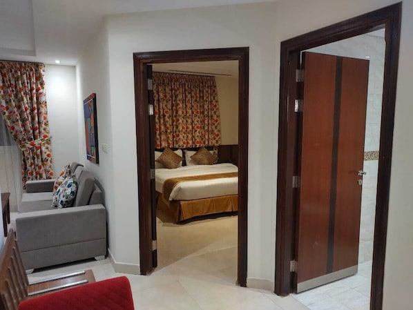 A hotel room with a bed, a sofa, and a red chair.
