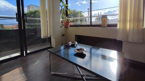 Une chambre moderne avec une grande fenêtre, une plante en pot, une table avec un bol et un objet décoratif posé sur le rebord de la fenêtre.