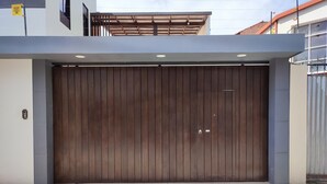 Un bâtiment moderne doté d’une grande porte en bois, d’un portail en métal et d’un chemin en béton menant à l’entrée.