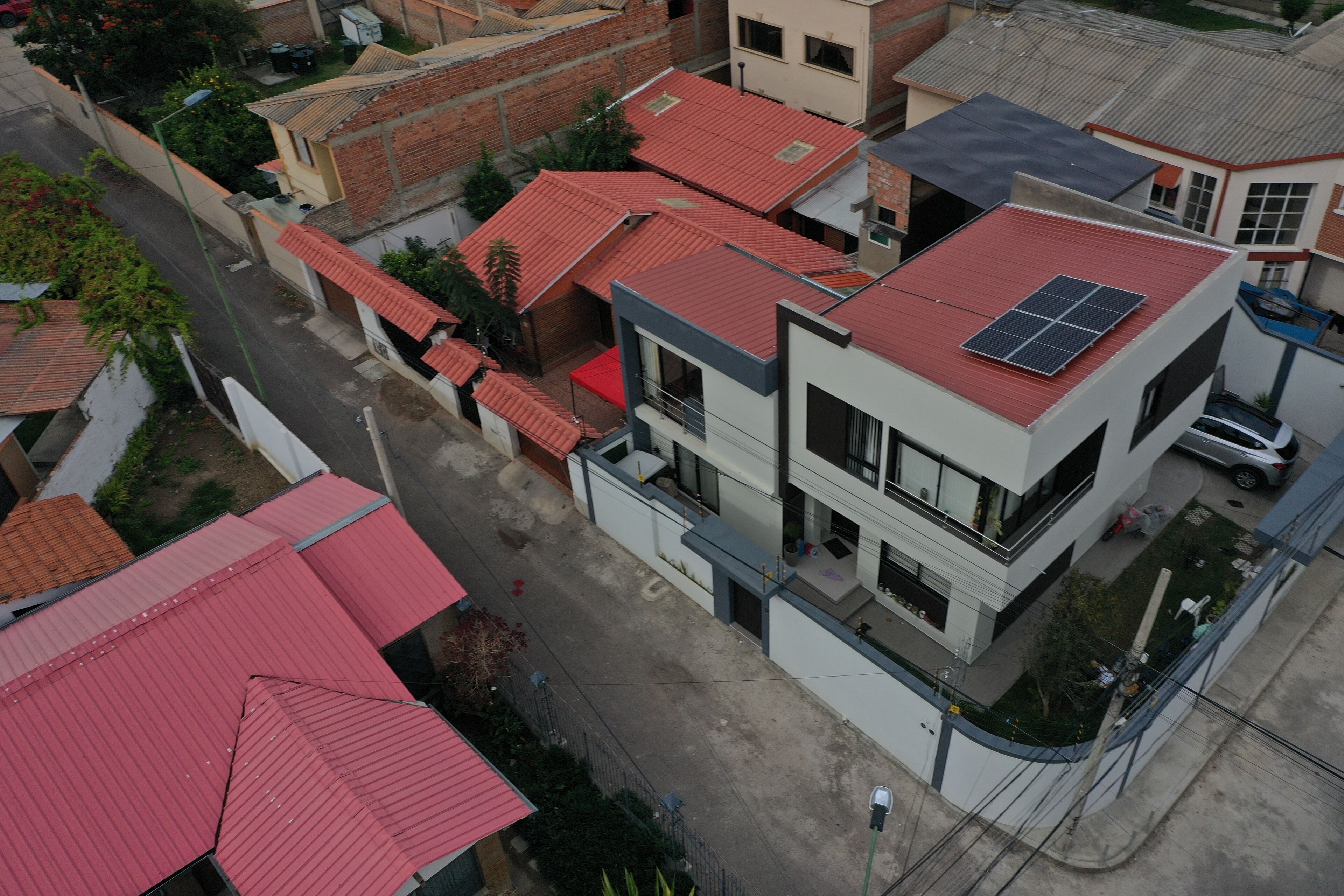 A multi-story building with a red-tiled roof, a solar panel on the top floor, and a visible balcony.