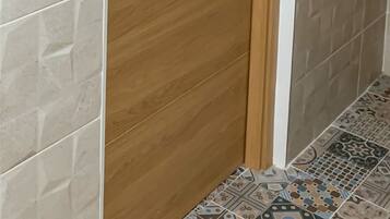 A wooden door with the number 9, a black door handle, and a wall with patterned tiles.